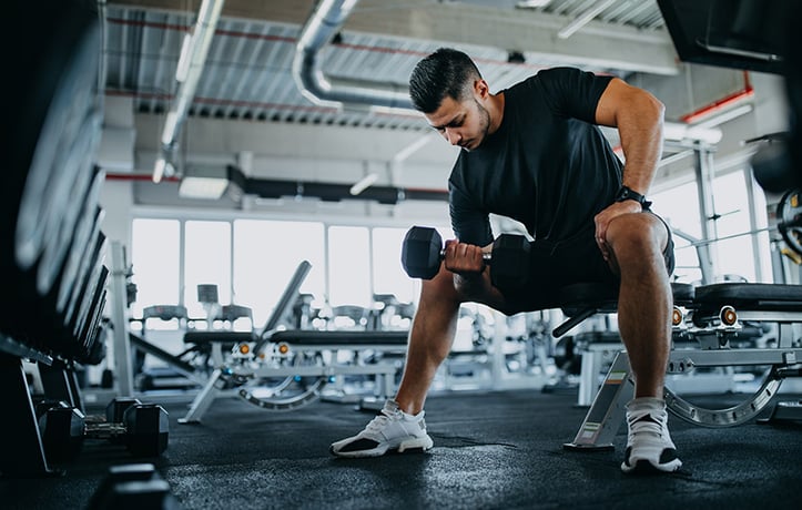 man doing a seated bicep curl with hard lying on inside of knee